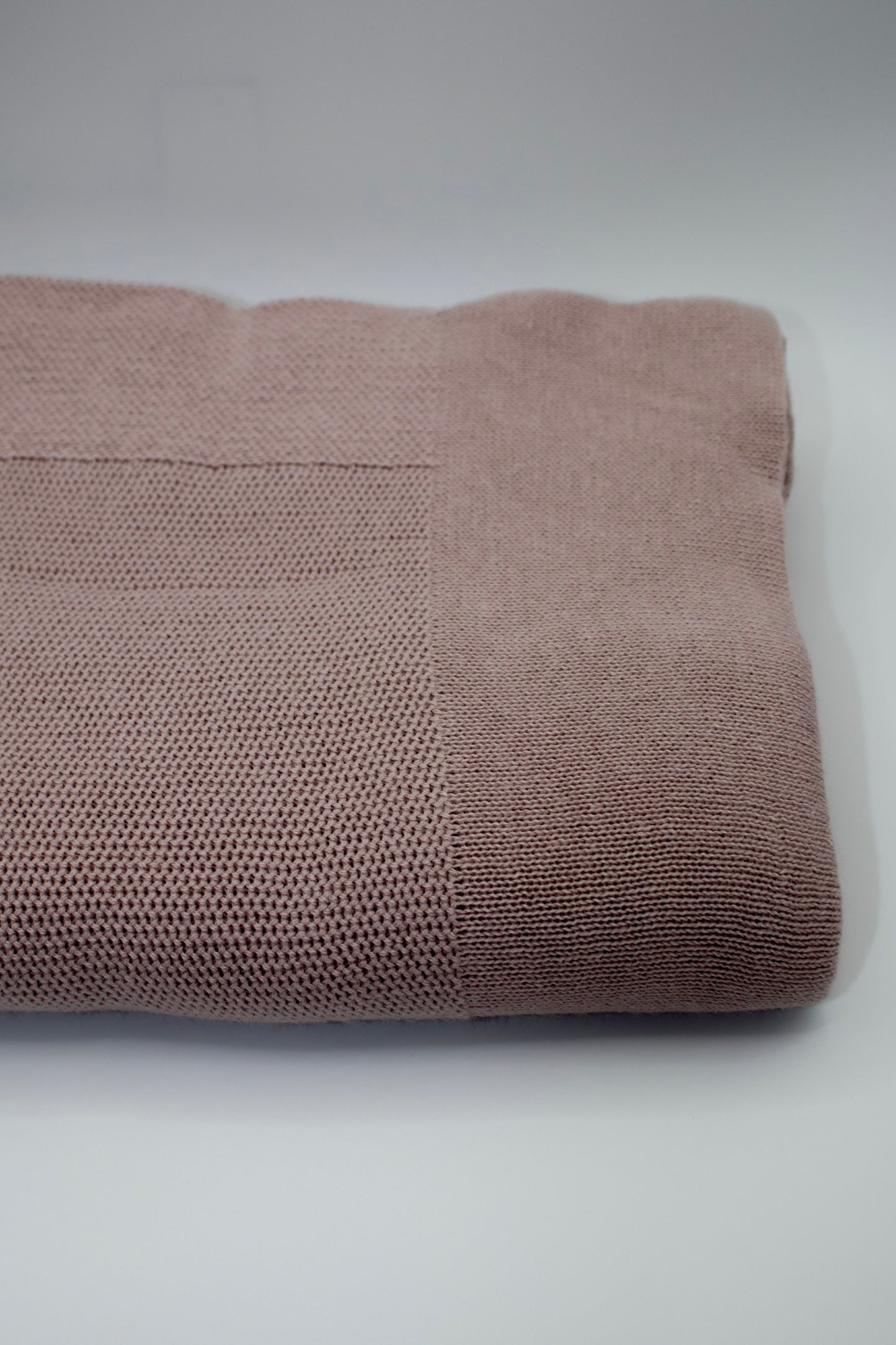 Folded mauve blanket on a white background