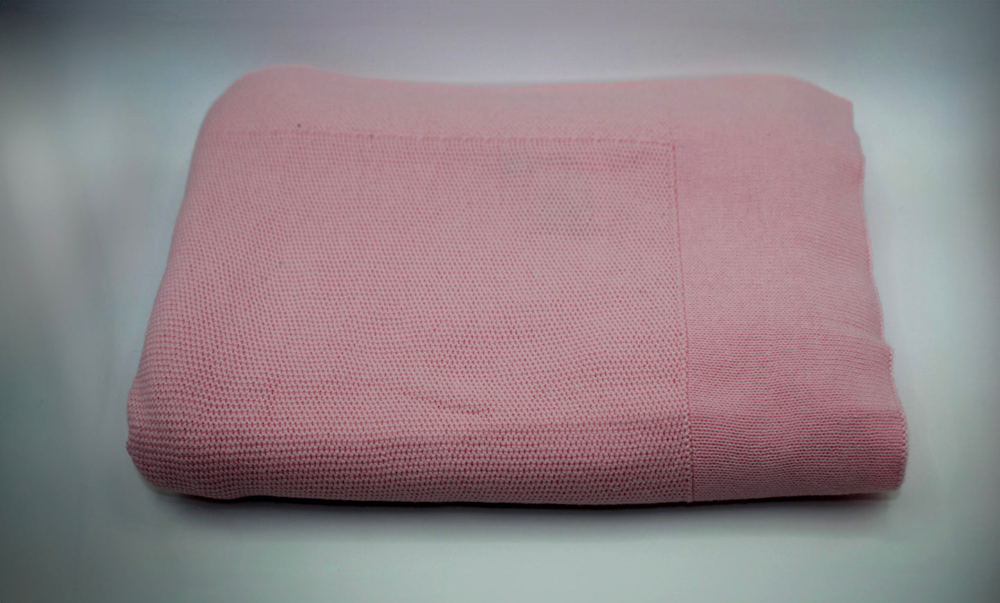 Folded pink blanket on a gray background