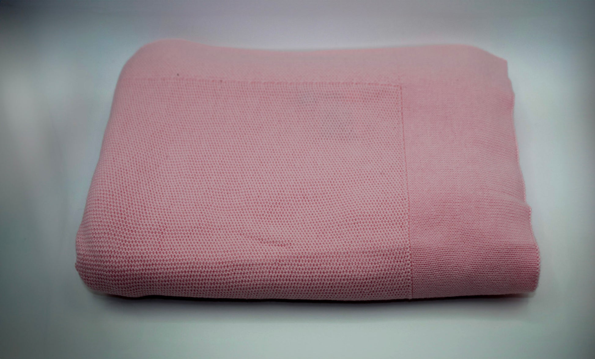 Folded pink blanket on a gray background