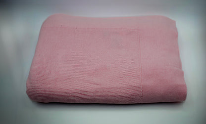 Folded pink blanket on a gray background