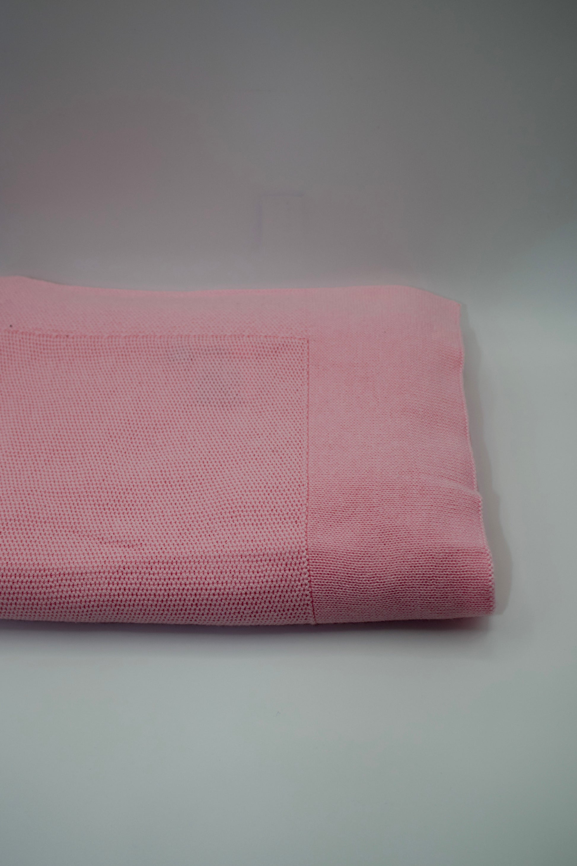 Rolled pink blanket on a gray background