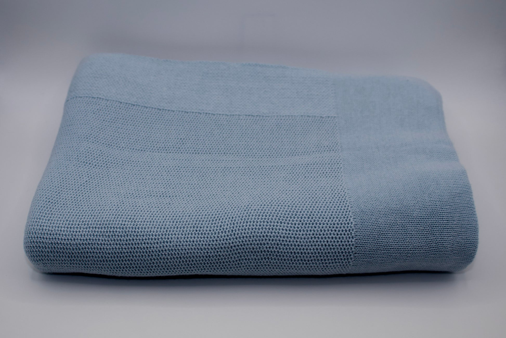 Folded blue textured blanket on a gray background