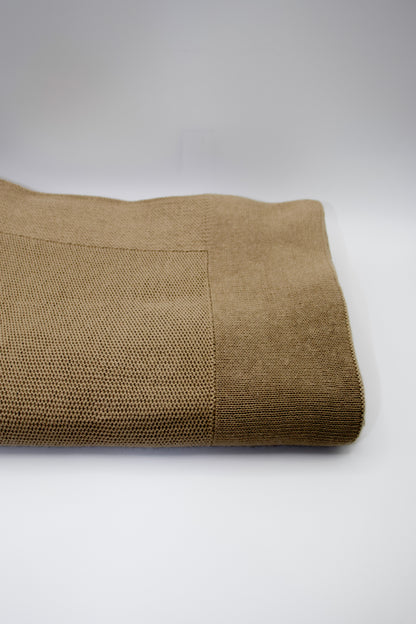 Folded brown blanket on a white background