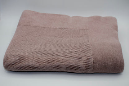 Folded mauve textured blanket on a light gray background