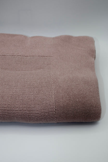 Folded mauve blanket on a white background