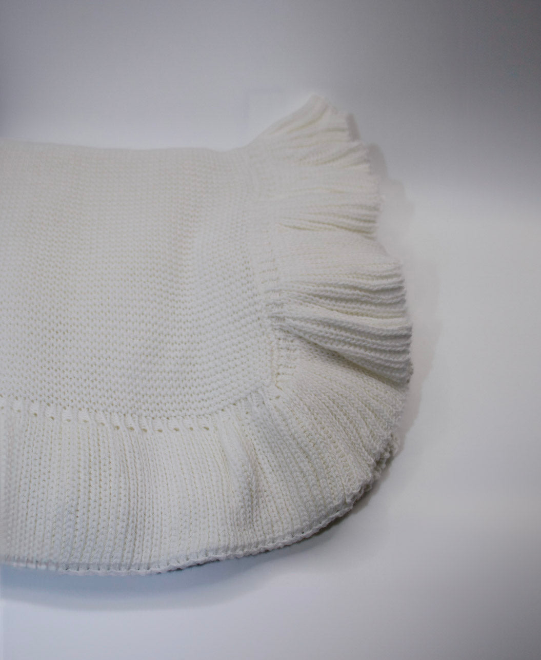 White knitted blanket on a gray background